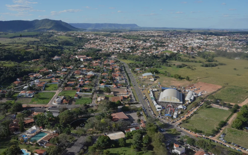 Vista aérea da Cidade de São Pedro, destacando áreas verdes e ruas arborizadas, com o céu azul ao fundo.