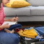 Jovem organizando roupas e itens essenciais, seguindo um checklist de viagem para se preparar antes de viajar.