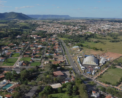 Vista aérea da Cidade de São Pedro, destacando áreas verdes e ruas arborizadas, com o céu azul ao fundo.